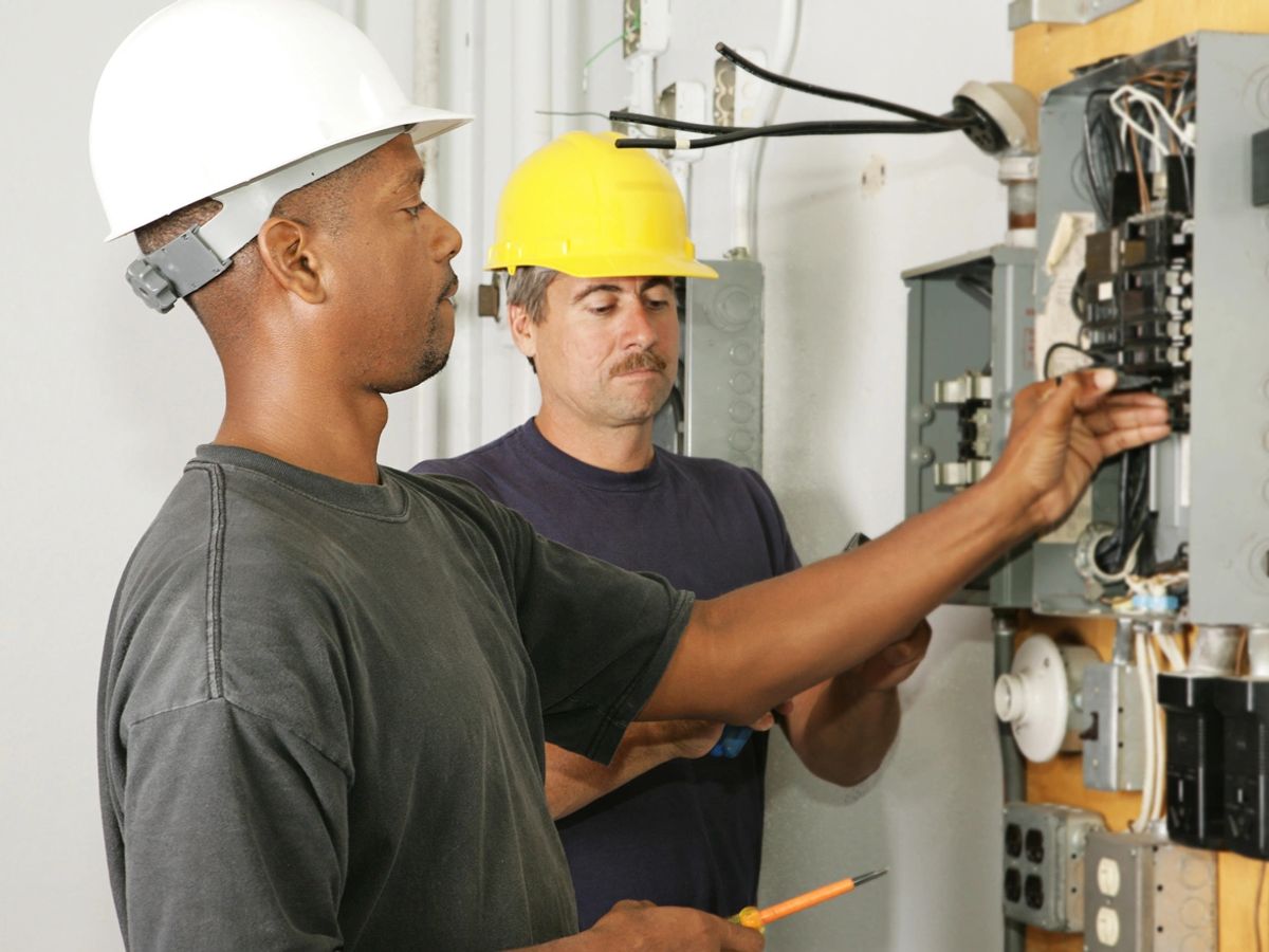 Electrical professionals working on a distribution panel